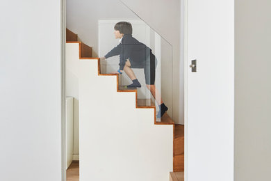 Diseño de escalera en U contemporánea de tamaño medio con escalones de madera, contrahuellas de madera y barandilla de vidrio