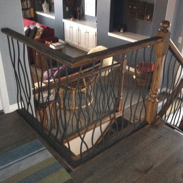 BENT iron design interior railing with a distressed wood handrail and base