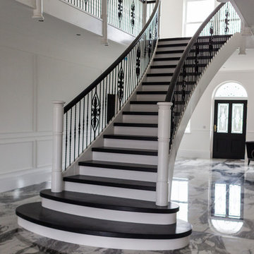 black and white curved staircase with wrought iron spindles