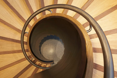 Modelo de escalera curva contemporánea grande con escalones de madera y contrahuellas de madera