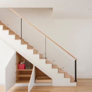 Foto di una scala a rampa dritta minimalista di medie dimensioni con pedata in legno, alzata in legno e parapetto in cavi