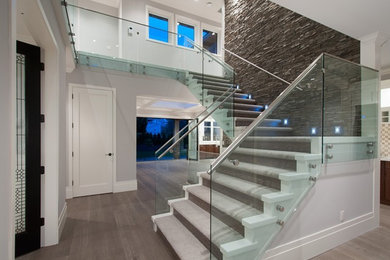 На фото: большая угловая деревянная лестница в стиле неоклассика (современная классика) с ступенями с ковровым покрытием