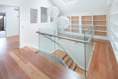 Пример оригинального дизайна: п-образная деревянная лестница среднего размера в современном стиле с деревянными ступенями и стеклянными перилами
