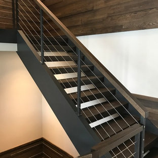 Idee per un'ampia scala a "L" minimalista con pedata in legno, alzata in metallo e parapetto in cavi