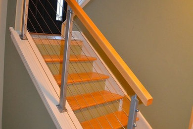 Immagine di una scala a rampa dritta design di medie dimensioni con pedata in legno e nessuna alzata