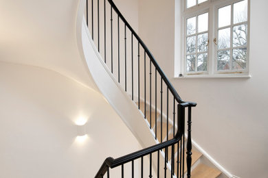 На фото: винтовая лестница в современном стиле с деревянными ступенями, крашенными деревянными подступенками и металлическими перилами