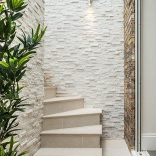 This is an example of a small contemporary curved staircase in London with tiled risers.