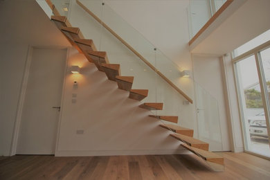 Design ideas for a medium sized modern wood floating glass railing staircase in Dublin with open risers.