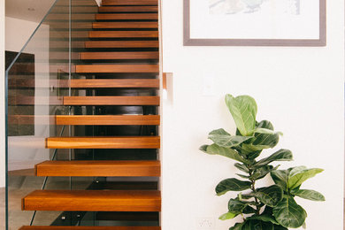 Idée de décoration pour un grand escalier flottant design avec des marches en bois et un garde-corps en verre.