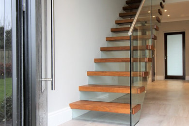 This is an example of a medium sized modern wood straight staircase in Dublin with glass risers.