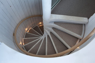 Imagen de escalera de caracol costera de tamaño medio sin contrahuella con escalones de hormigón y barandilla de varios materiales