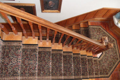 Large wooden curved staircase photo in Boston with wooden risers