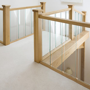 Carpeted Staircase featuring Glass Balustrades
