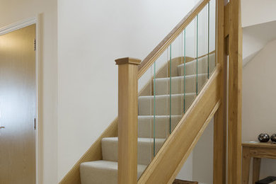 На фото: изогнутая лестница среднего размера в современном стиле с ступенями с ковровым покрытием, ковровыми подступенками и перилами из смешанных материалов с