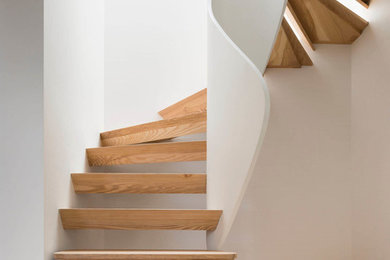 Ejemplo de escalera curva minimalista sin contrahuella con escalones de madera