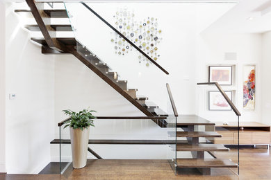 Ejemplo de escalera en U contemporánea sin contrahuella con escalones de madera y barandilla de vidrio