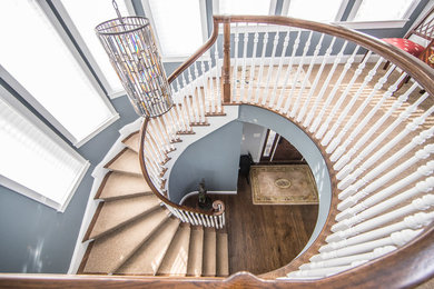 Diseño de escalera curva clásica de tamaño medio con escalones de madera, contrahuellas de madera y barandilla de madera