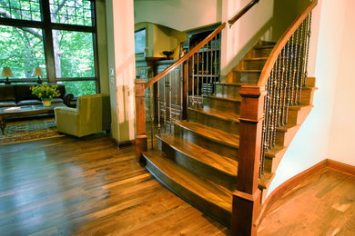 Imagen de escalera curva de estilo americano grande con escalones de madera y contrahuellas de madera