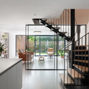 This is an example of a medium sized modern wood curved metal railing staircase in Manchester with metal risers.