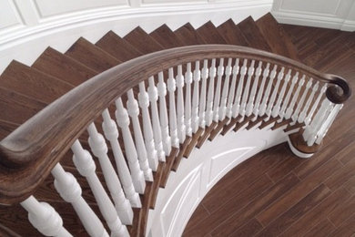 Large trendy wooden curved staircase photo in New York with wooden risers