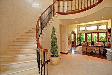 Inspiration for a medium sized mediterranean curved metal railing staircase in Los Angeles with limestone treads and limestone risers.
