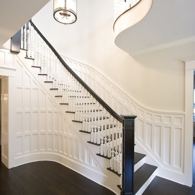 Example of a large classic wooden curved wood railing staircase design in New York with painted risers
