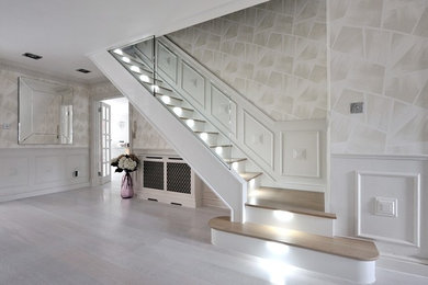 Ejemplo de escalera curva actual grande con escalones de madera, barandilla de vidrio y contrahuellas de madera pintada