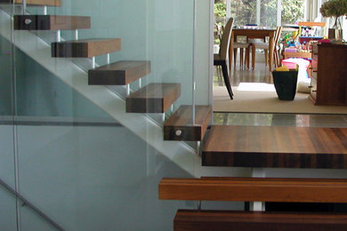 На фото: угловая лестница среднего размера в современном стиле с деревянными ступенями без подступенок с