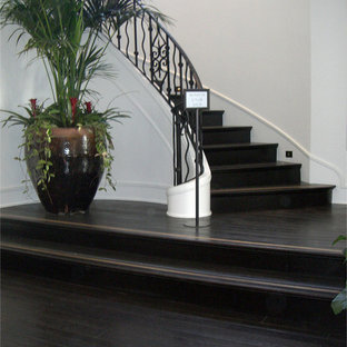 Immagine di un'ampia scala curva chic con pedata in legno e alzata in legno