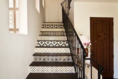 Foto de escalera mediterránea con escalones de madera, contrahuellas con baldosas y/o azulejos y barandilla de metal