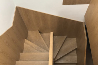 Diseño de escalera de caracol actual con escalones de madera, contrahuellas de madera y barandilla de madera