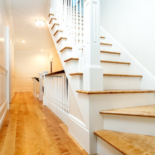 Example of a large ornate wooden curved staircase design in Boston with painted risers
