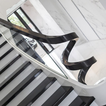 Curved black and white wooden staircase with glass balustrade and glass landing