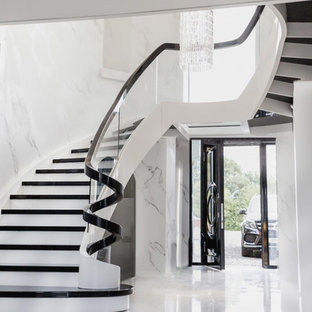 Idee per una grande scala curva moderna con pedata in legno, alzata in legno e parapetto in vetro