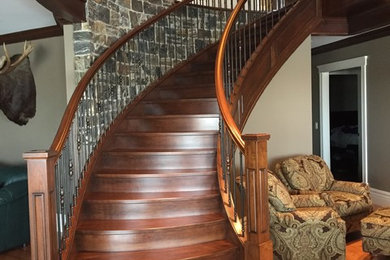 Foto de escalera curva tradicional de tamaño medio con escalones de madera, contrahuellas de madera y barandilla de madera