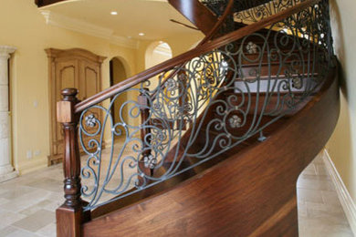 Diseño de escalera curva clásica grande con escalones de madera, contrahuellas de madera y barandilla de varios materiales
