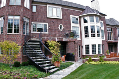 Large elegant slate curved metal railing staircase photo in Detroit with metal risers