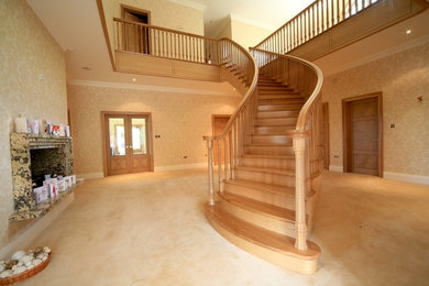 Ejemplo de escalera curva contemporánea grande con escalones de madera y contrahuellas de madera