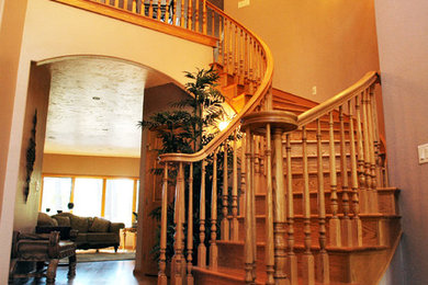 Large transitional wooden curved wood railing staircase photo in Other with wooden risers