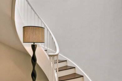Foto de escalera curva clásica renovada pequeña con escalones de madera, contrahuellas de madera y barandilla de metal