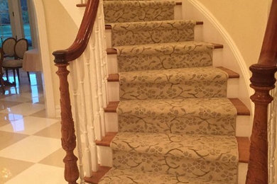 Large transitional wooden curved staircase photo in New York with painted risers
