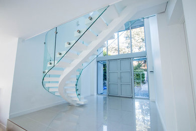 Inspiration for a modern curved staircase in London with open risers and feature lighting.
