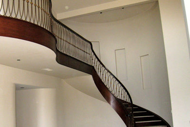 Example of a large trendy curved staircase design in San Diego with wooden risers