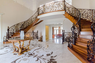 Staircase - huge traditional wooden curved metal railing staircase idea in Toronto with wooden risers