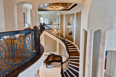 Стильный дизайн: огромная изогнутая лестница в классическом стиле с деревянными ступенями и крашенными деревянными подступенками - последний тренд