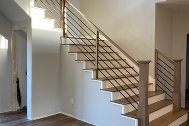 Ejemplo de escalera en L actual grande con escalones de madera, contrahuellas de madera pintada y barandilla de varios materiales