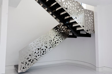 Ejemplo de escalera suspendida minimalista grande con escalones con baldosas y contrahuellas de metal