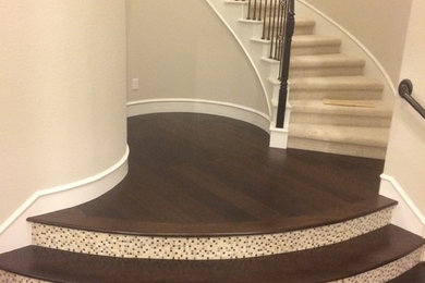 Large traditional wood curved metal railing staircase in Houston with tiled risers.