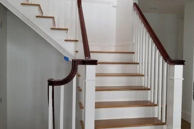Идея дизайна: угловая лестница в классическом стиле с деревянными ступенями, крашенными деревянными подступенками и деревянными перилами