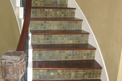Ejemplo de escalera curva clásica de tamaño medio con escalones de madera, contrahuellas con baldosas y/o azulejos y barandilla de varios materiales